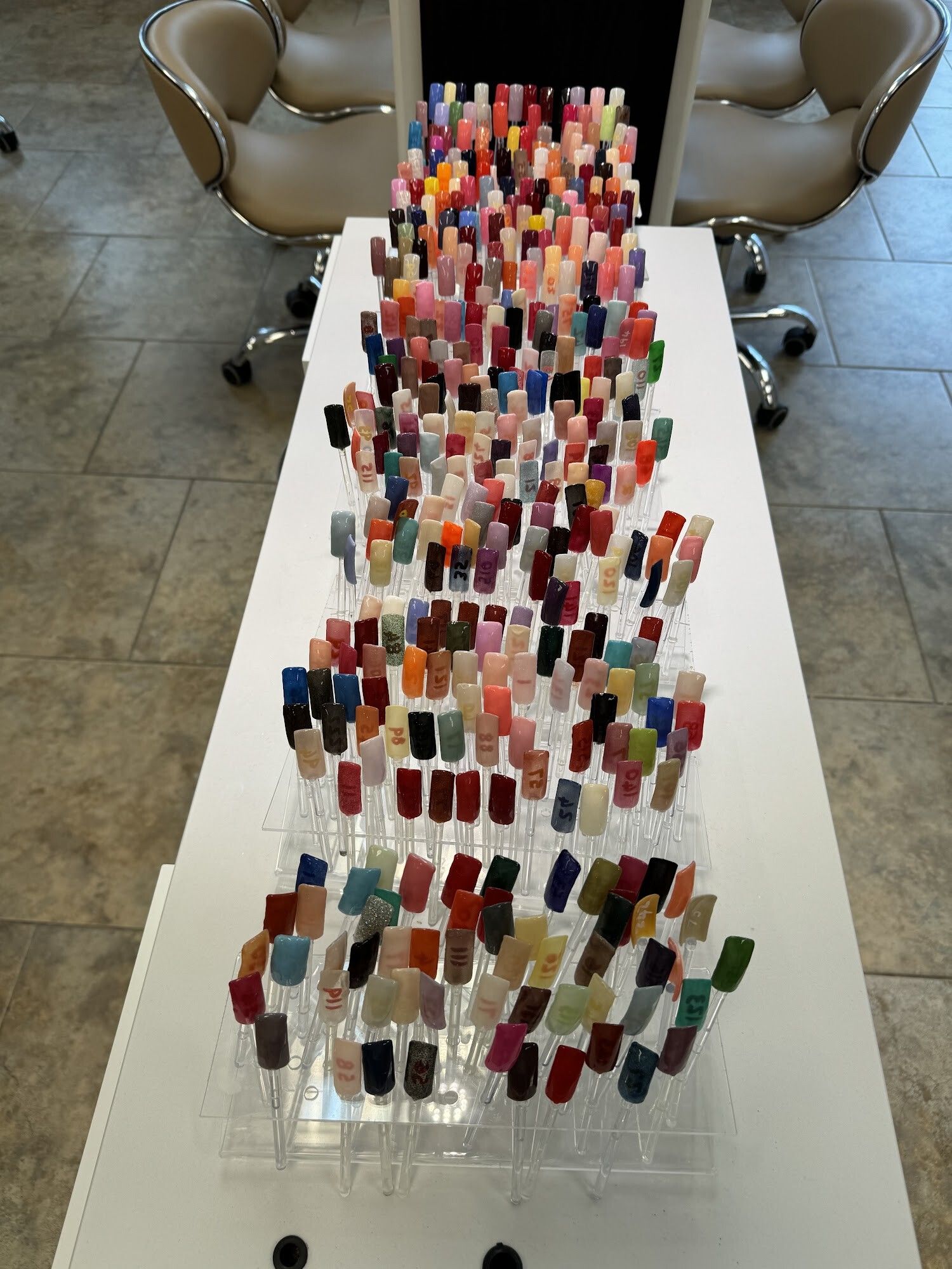 Rows of nail color swatches arranged on a white table